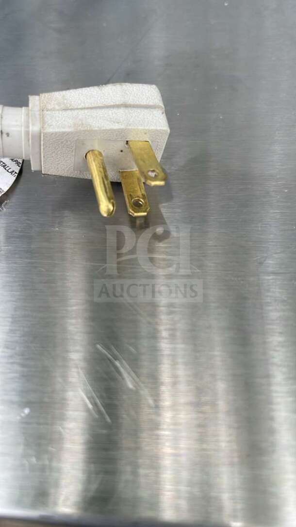 Plug of True TUC-27-HC undercounter refrigerator on stainless steel surface, showing three-prong design.