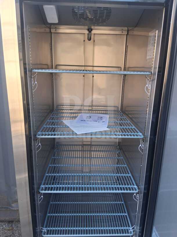 Dukers D28R 27.5" reach-in refrigerator, right hinge solid door, 4 metal shelves, clean interior, visible user manual.
