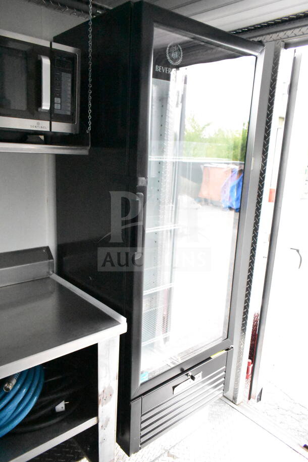 Interior of a 1993 GMC Step Van showing a stainless steel counter, built-in Sentinel microwave, and a glass-door refrigerator.