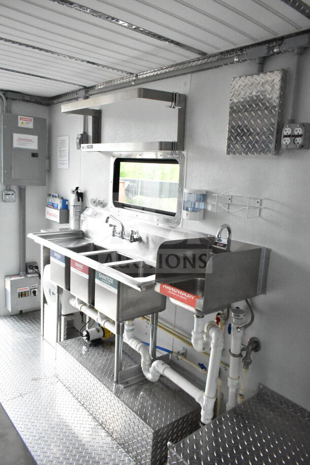 Interior view of a 1993 GMC Step Van, featuring a stainless steel triple sink setup with wash, rinse, sanitize labels, and a handwashing station. Bright metal shelving, diamond plate flooring, and utility connections visible.