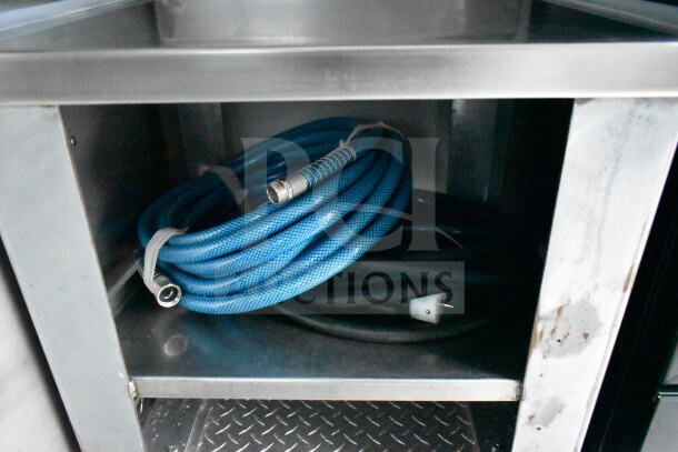 Coiled blue and black hoses inside a storage compartment of a 1993 GMC Step Van.