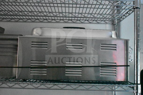 Stainless steel chafing dish with vented lid on a metal shelf. Used condition, suitable for catering or food service.