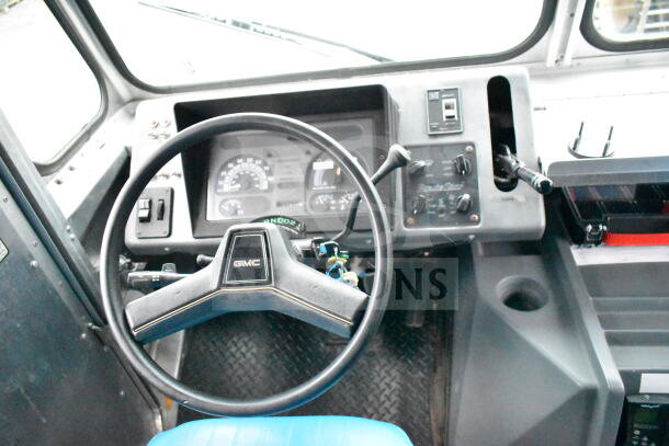 Interior of 1993 GMC Step Van, featuring dashboard controls, steering wheel with GMC logo, and visible odometer.
