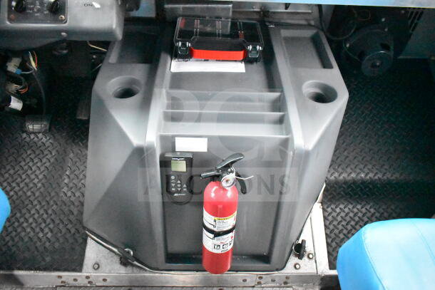 Interior view of a 1993 GMC Step Van featuring control panels, a fire extinguisher, and a gray storage unit.