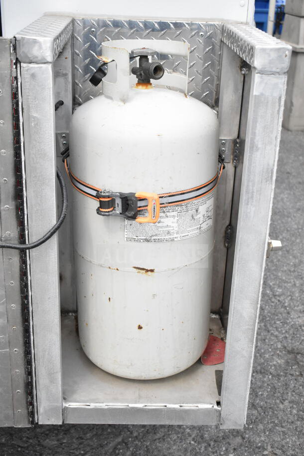 GMC Step Van propane tank compartment, featuring a secured white propane cylinder with minor rust, diamond plate lining.