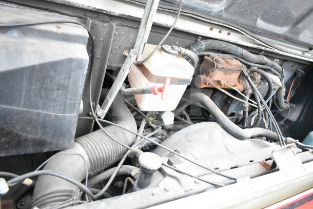 Engine compartment of 1993 GMC Step Van showing hoses, wires, and components; indicating vehicle's condition.