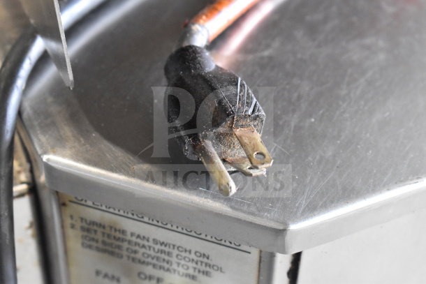 Close-up of a power plug resting on the metal surface of an XLT XLT3240-TS commercial conveyor pizza oven.