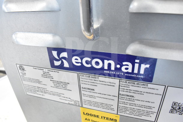 Econ-Air EA-USBI11DD-RM commercial exhaust fan, silver, with safety and installation labels. Model details and contact info visible.