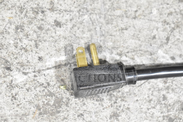 A close-up of a three-prong electrical plug on a textured surface.