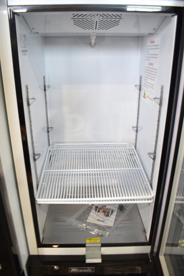 Brand new 2023 Migali C-10RM-HC commercial cooler, single door, 115V, on casters, visible interior shelving and manual.
