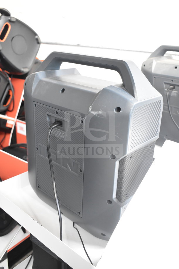 Ion speaker store display, gray with handle, shows scuffs on surface, charging port visible. Includes three units.