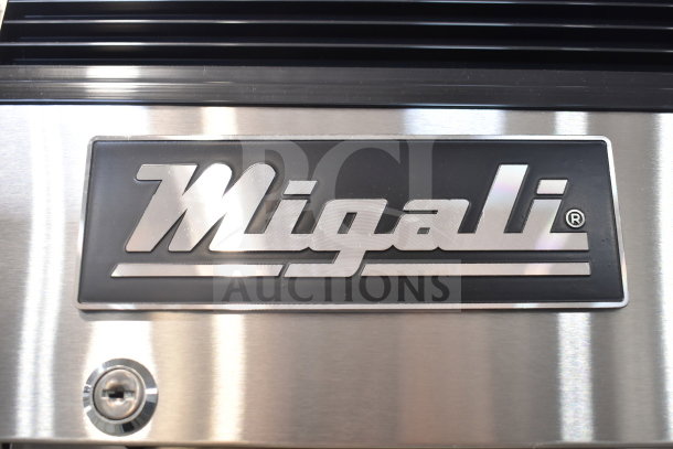 Migali logo on the stainless steel surface of a 2019 Migali C-1FB-HC commercial freezer, showing branding detail.