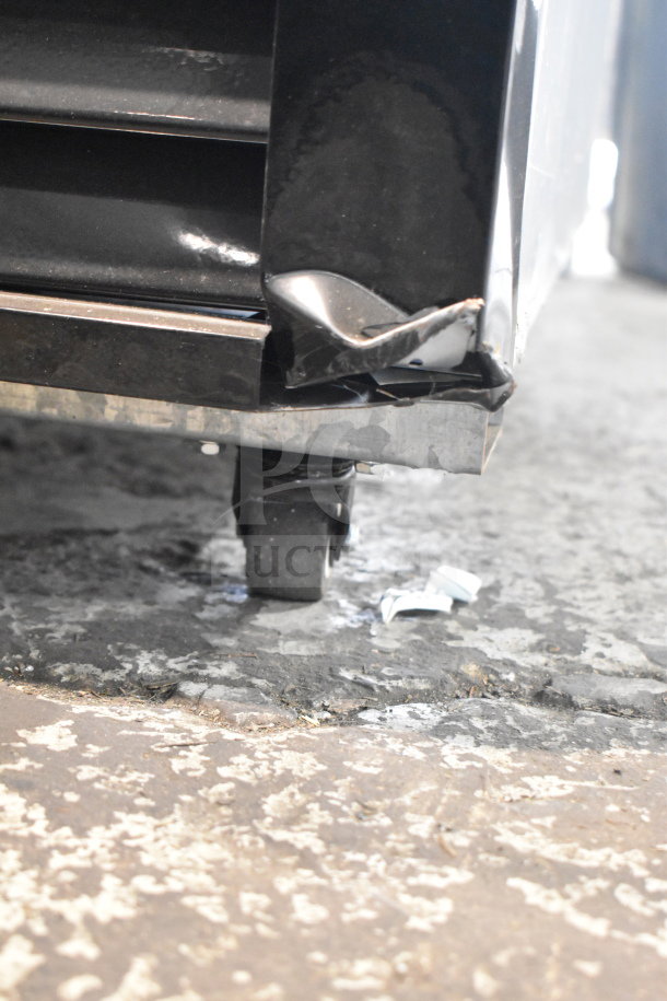 Migali C-72FM freezer's scratched bottom corner with visible dent, showing commercial caster on concrete floor.