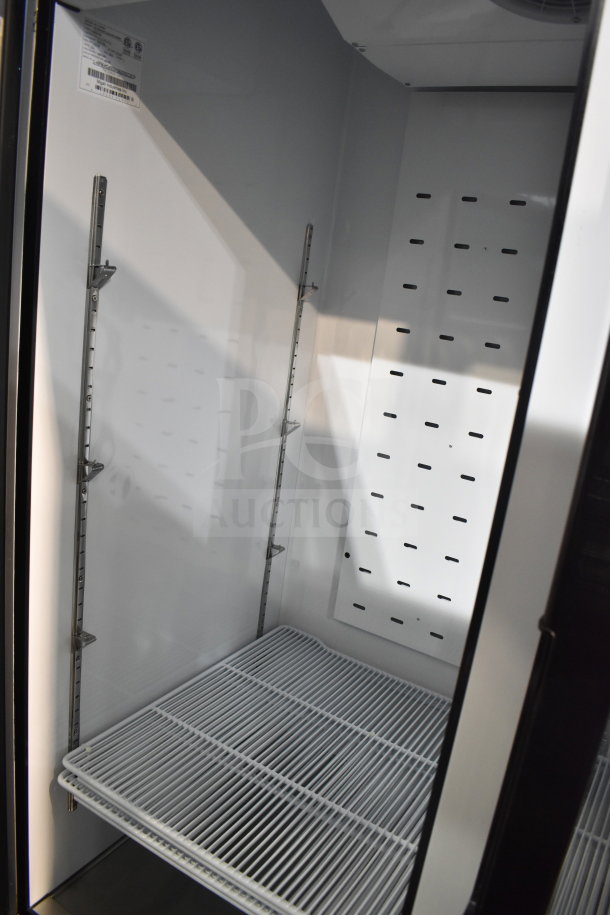 Brand new Migali C-49FM-HCe 3-door reach-in freezer, scratch and dent, interior view, shelves, commercial casters.