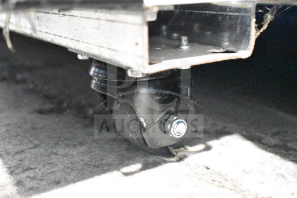 Commercial caster on Migali C-49FM-HCe freezer, featuring durable construction. Slight scratches present.