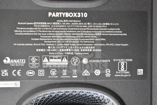 Close-up of a label on a JBL Partybox 310 speaker, showing model details, compliance certifications, and power specifications.