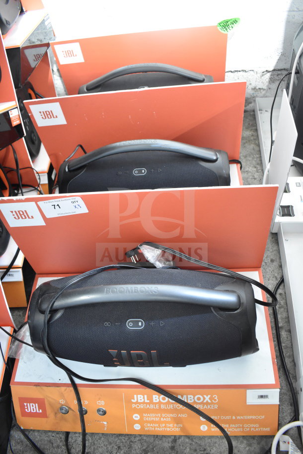 Three JBL Boombox 3 speakers on store display. Features include massive sound, waterproof design, and deep bass.