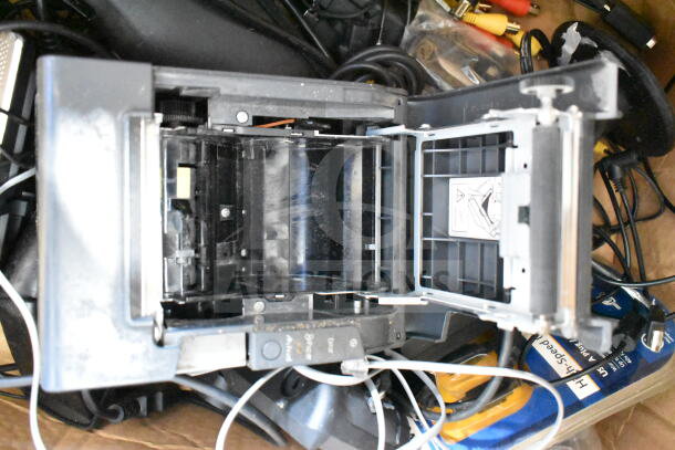 Various electronics including open casing of a device, cables, and high-speed USB packaging in cluttered condition.