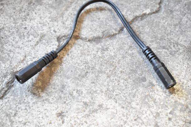 A black cable with connectors, likely part of a security DVR system, shown on a textured surface.