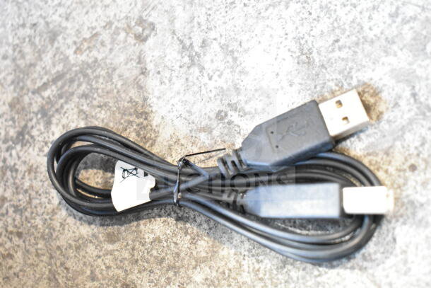 Coiled USB cable on a textured surface with black connectors and a white tag attached.