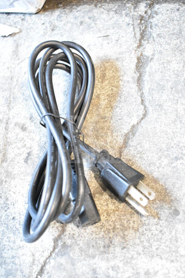 Coiled black power cable, three-prong plug, labeled "AWG 18", in good condition on concrete surface.