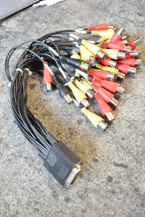 Bundle of assorted audio and video cables with red, yellow, and black connectors, shown on a concrete surface.