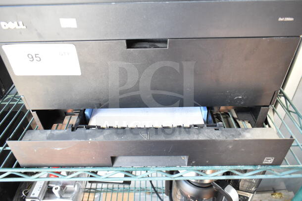 Dell 2350dn Countertop Printer on metal shelf, paper loaded. Visible model marking, tag reads "95 QTY". Good condition.