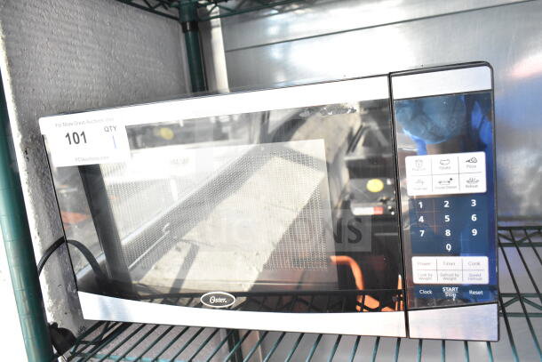 Oster OGYU701 countertop microwave oven, 120 volts, 1 phase, digital controls, silver and black finish, in good condition.