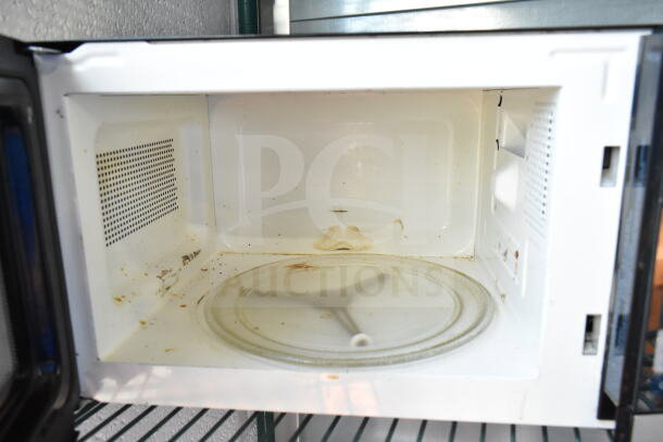 Oster OGYU701 Countertop Microwave Oven, white interior, visible wear, 120 Volts, 1 Phase, glass turntable included.