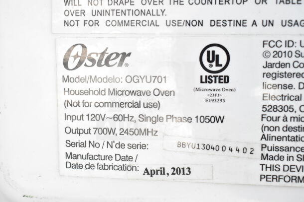 Oster OGYU701 Countertop Microwave Oven label, 120V, 700W. Model and serial information visible, manufactured April 2013.
