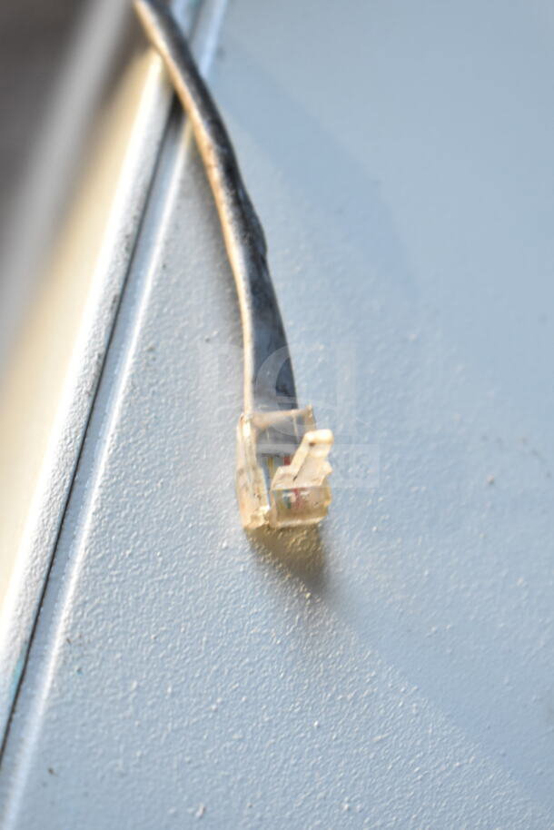 Clover Cash Drawer cable connector close-up. Silver surface, condition appears used.