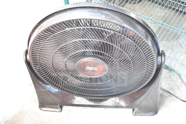 Black Best Comfort fan with mesh grille, circular design, and sturdy base; logo visible at center. Moderate wear.