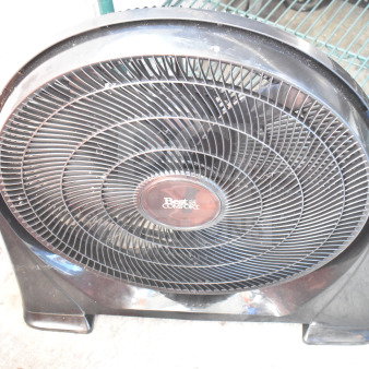 Black Best Comfort fan with mesh grille, circular design, and sturdy base; logo visible at center. Moderate wear.