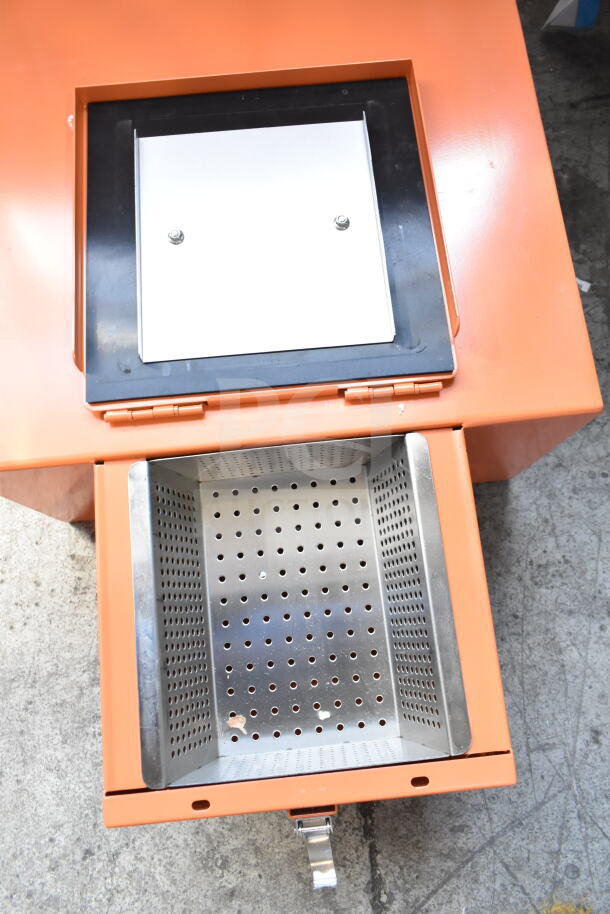 BRAND NEW Fryclone Oil Caddy, scratch and dent, features perforated metal basket, orange body, stainless steel lid.