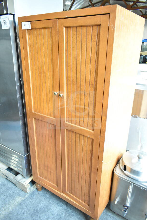 Wood pattern 2-door cabinet with vertical grooves, gold knobs, and sturdy wooden feet. Slight surface wear visible.