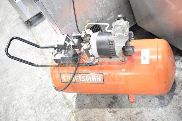 Craftsman Air Compressor, orange tank with black motor, used condition. Visible Craftsman logo on tank, item labeled "115".