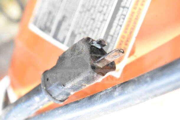 Craftsman air compressor power plug close-up. Black plug shows wear. Background label features maintenance instructions.