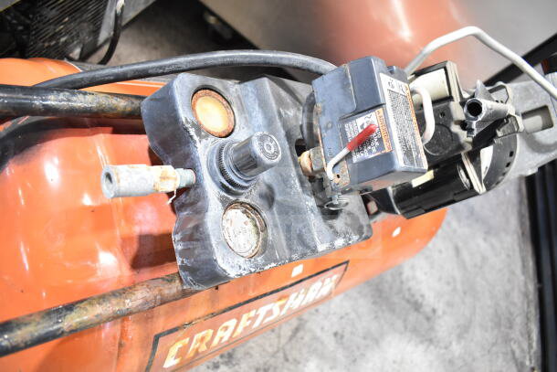 Craftsman air compressor, orange tank, visible gauges and switches, exhibiting signs of wear and rust, Craftsman logo present.