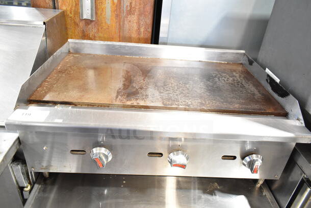 Commercial countertop gas-powered flat top griddle, stainless steel, three control knobs, used condition.