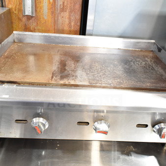 Commercial countertop gas-powered flat top griddle, stainless steel, three control knobs, used condition.
