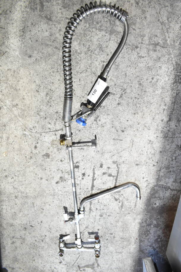 Industrial faucet with spray nozzle and flexible hose, stainless steel finish, model 130 on handle, good condition.