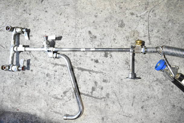 Chrome faucet with spray nozzle attachment, used condition, dual handles, and visible wear marks; industrial style.