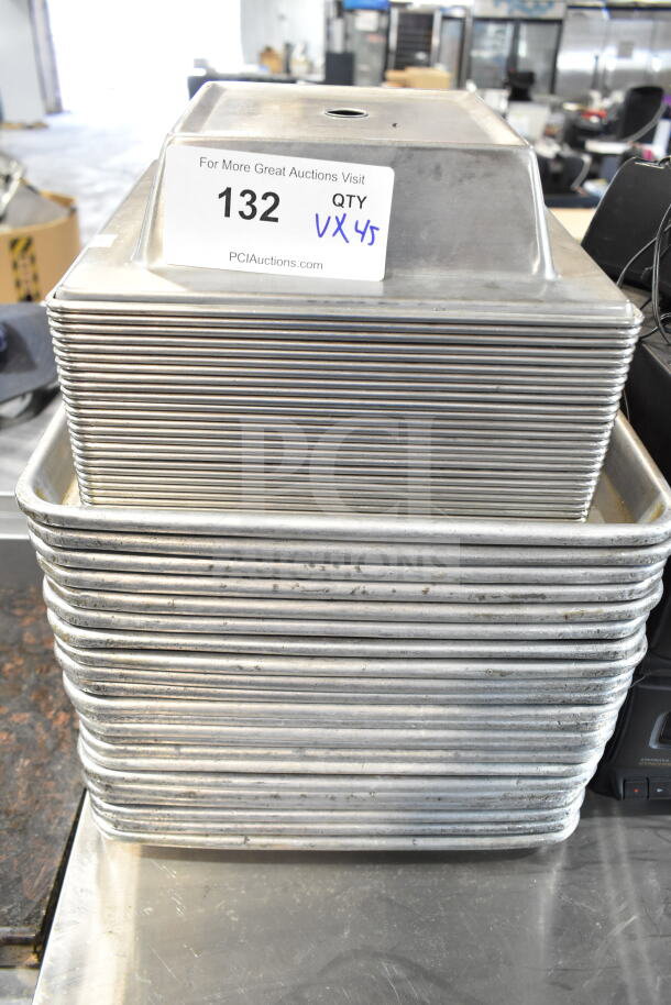 Stack of 45 various sized baking pans, silver metal, used condition, lot number 132, auction label visible.