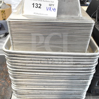 Stack of 45 various sized baking pans, silver metal, used condition, lot number 132, auction label visible.