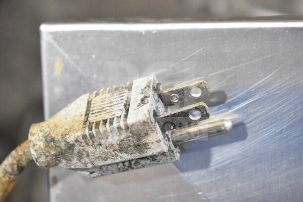 SureShot AC6.E countertop sugar dispenser plug, 120 volts, showing wear and grime, metal surface background.