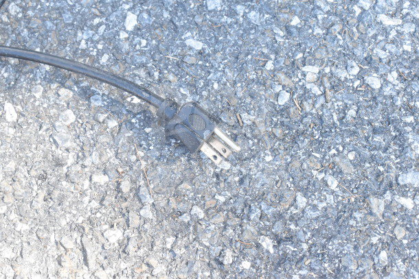 Electrical plug for a Galanz GL27BK Mini Cooler on a gravel surface, indicating electrical compatibility.