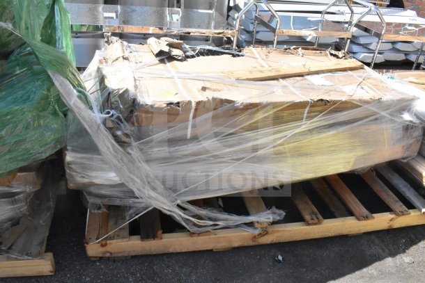 Four brand new scratch and dent auction items, including a pan rack and whiteboard, wrapped on a wooden pallet.