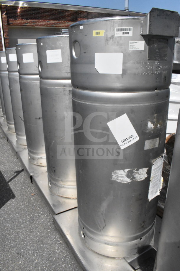 Four Sharpsville Container Tanks, silver, industrial-grade, marked with UN1280 for propylene oxide, scratch marks visible.