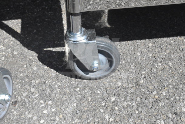 Close-up of a commercial caster wheel attached to a metal 3-tier cart, showing sturdy construction for mobility.