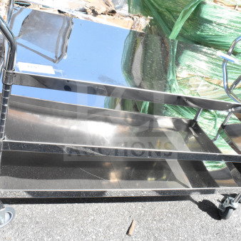 3 Tier metal utility cart with commercial casters, reflective finish, three shelves, signs of light wear, ideal for storage or transport.